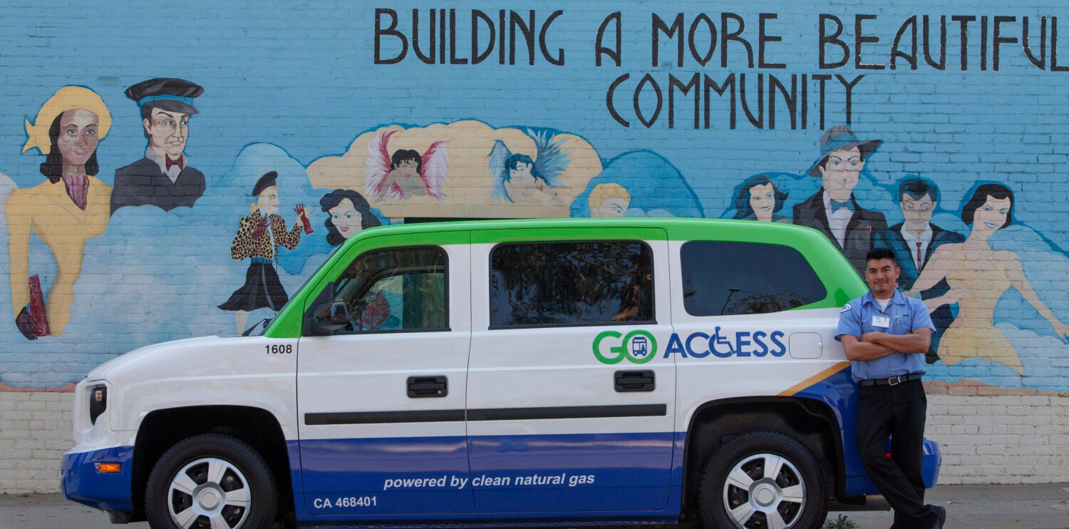 side view of paratransit vehicle in front of blue wall saying building a better community