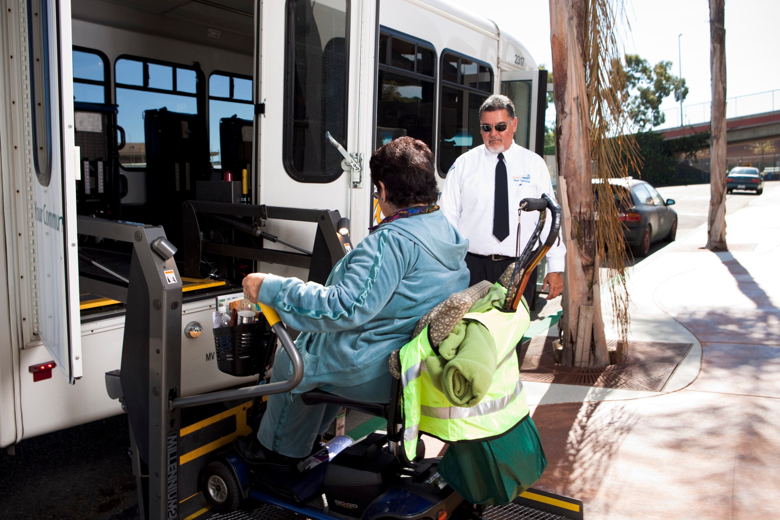 man in wheelchair using chair lift to get on the bus