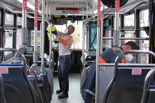 2 workers sanitizing the inside of a bus