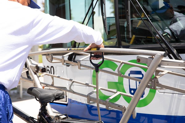 man pulling handle and lifting down the bus bike rack