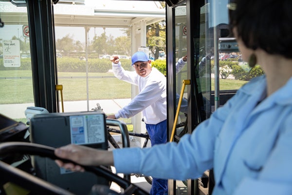 man with bike pointing to rack on front of bus